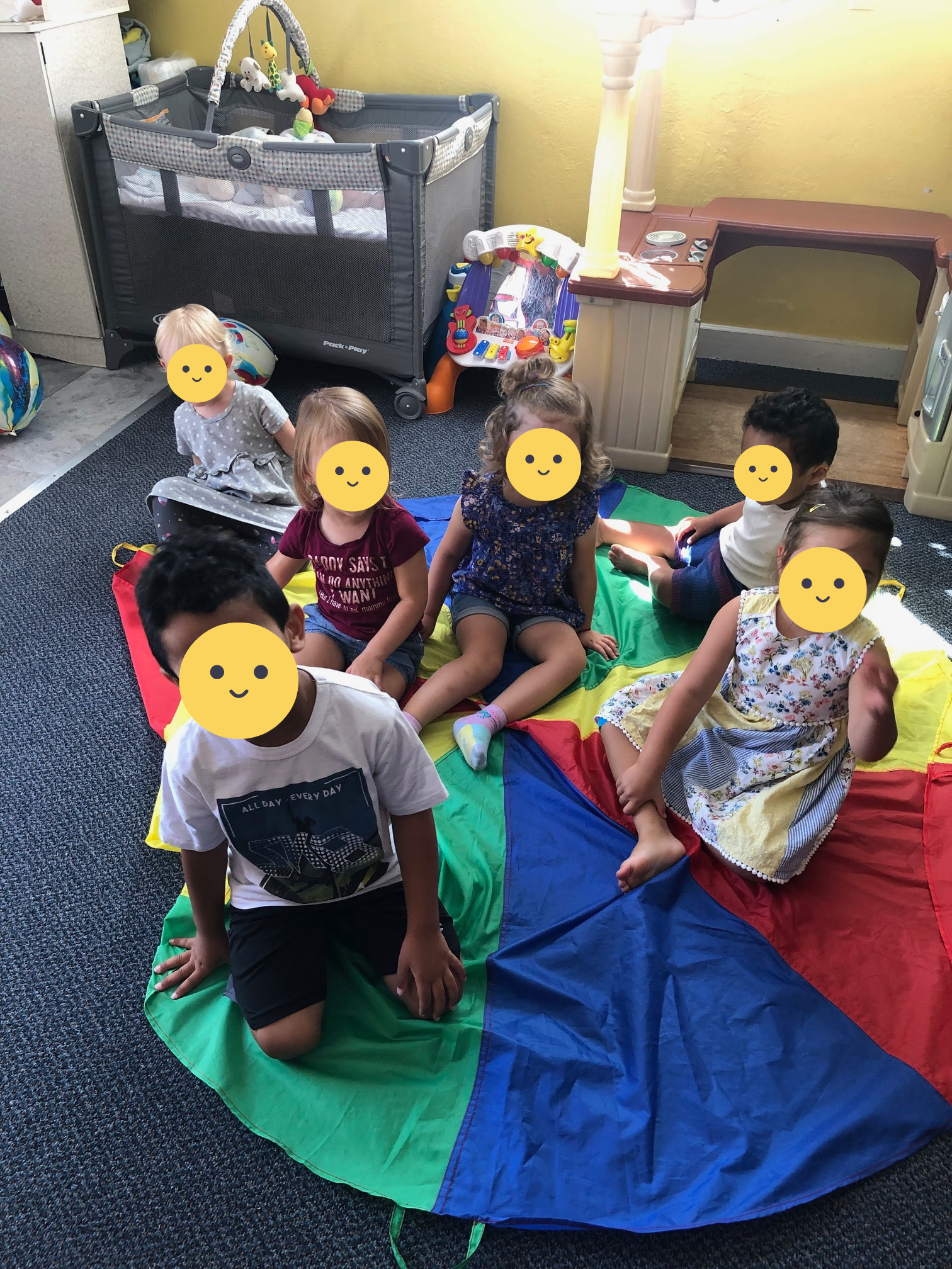 Children sitting on a colorful parachute.